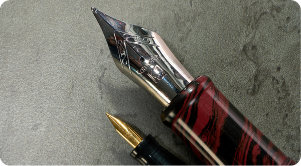 Photo of two fountain pen nibs, one huge & one tiny. 