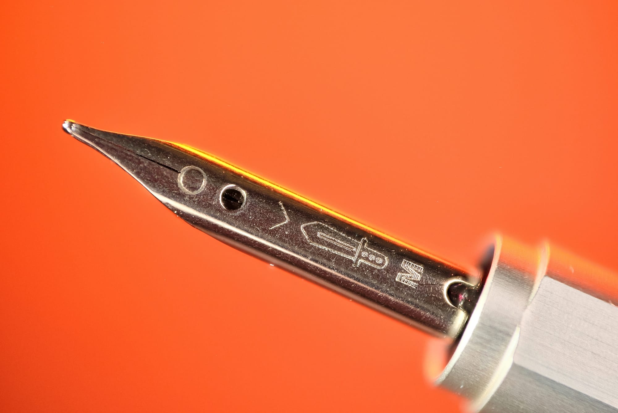Close-up of the Creator's medium nib with a sword engraving on an orange background
