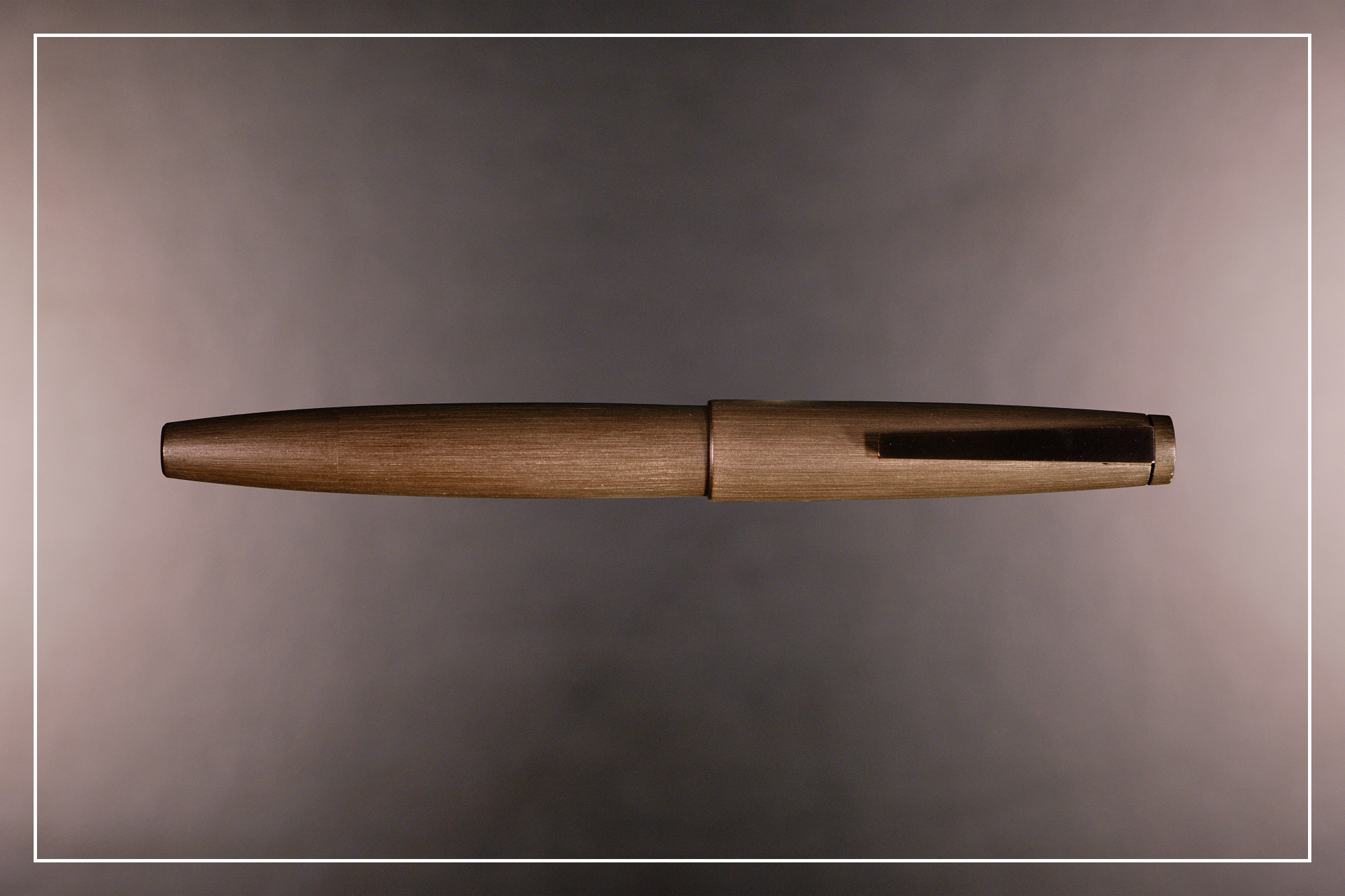 Photo of a brown Lamy 2000 fountain pen on a blurred grey background.