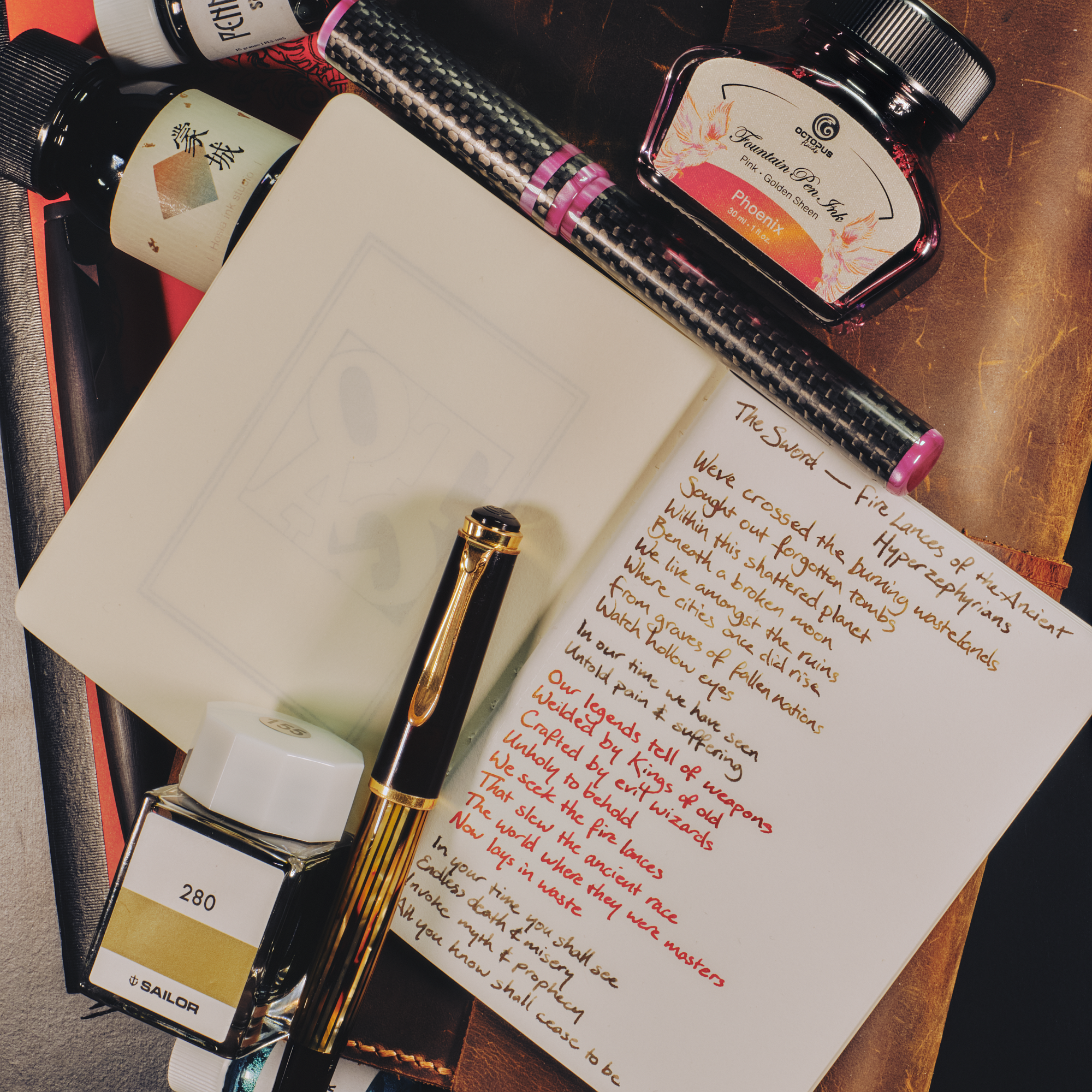 Photo of the 3 pens surrounded by the ink bottles they're filled with, on top of notebooks with a writing sample.