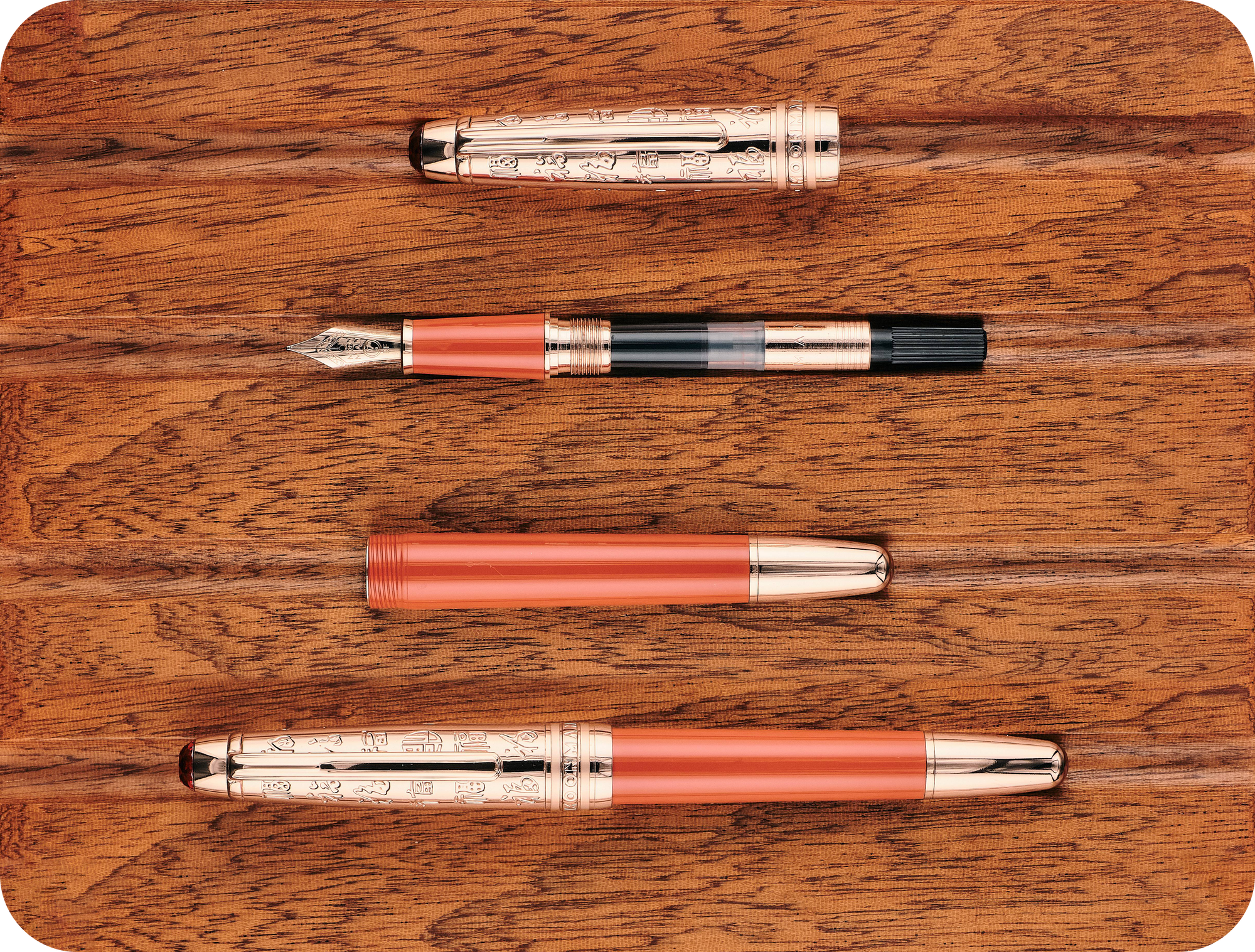 Overhead photo of the red & rose gold P135 with its cap on & fully disassembled on a wooden board