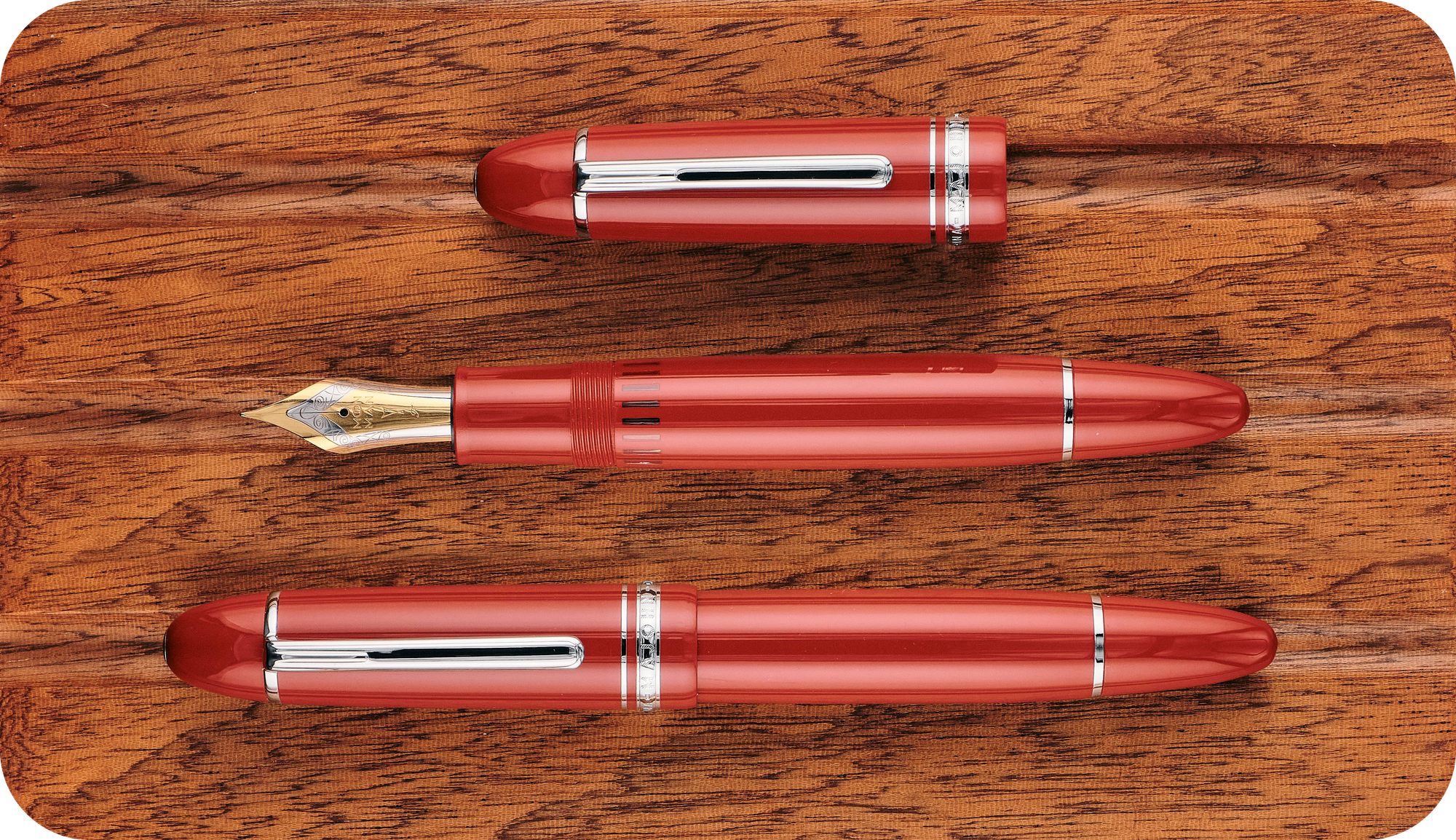 Overhead photo of the red P141 with its cap on & off on a wooden board