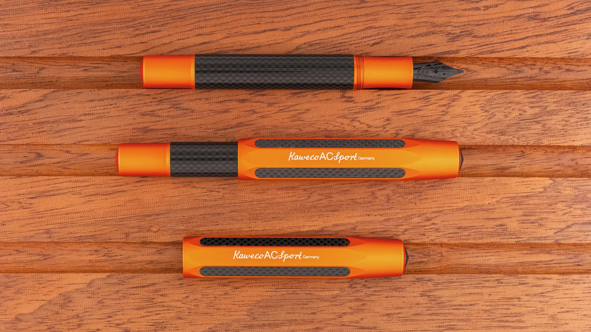 Overhead photo of an orange & carbon fibre pocket fountain pen on a wooden tray. The pen is shown capped and uncapped.