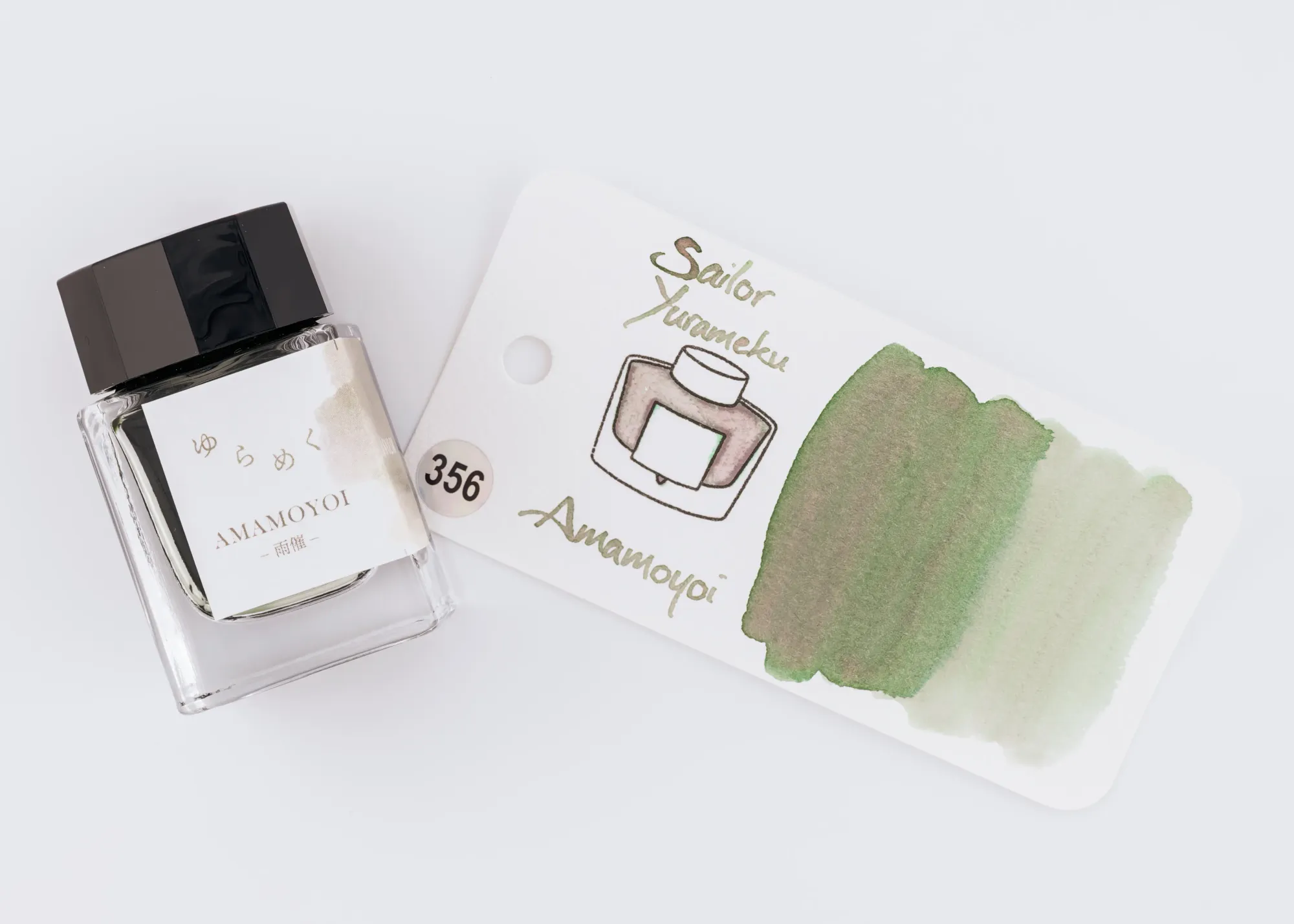 Overhead photo of a Sailor Yurameku ink bottle next to a swatch of the green, grey, & pink ink on a white background.