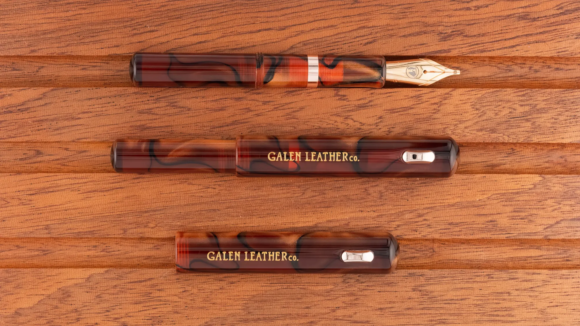 Overhead photo of a marbled amber/brown acrylic pocket fountain pen on a wooden tray. The pen is shown capped and uncapped.