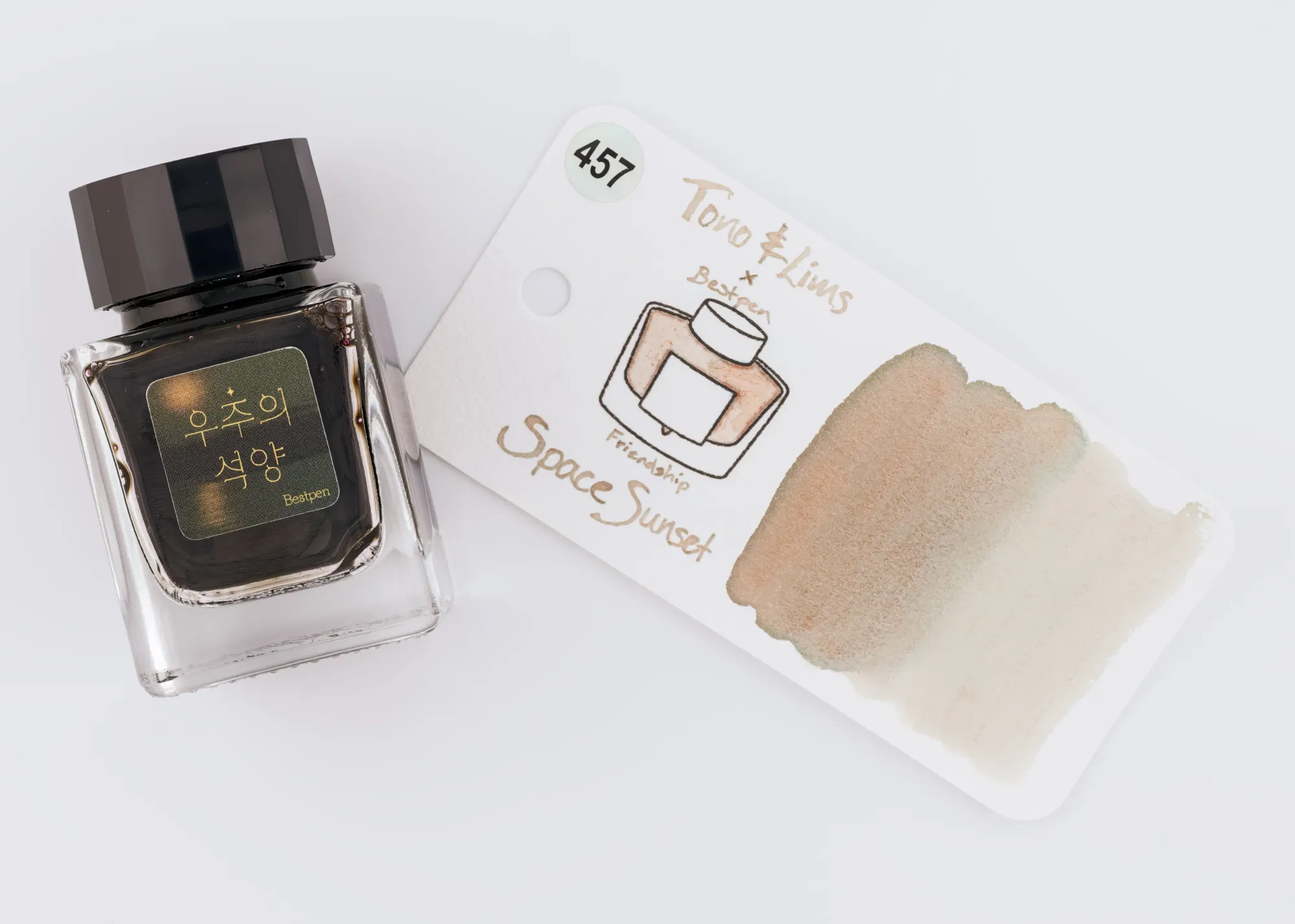 Overhead photo of a Tono & Lims ink bottle next to a swatch of the pale orange, grey, & teal ink on a white background.