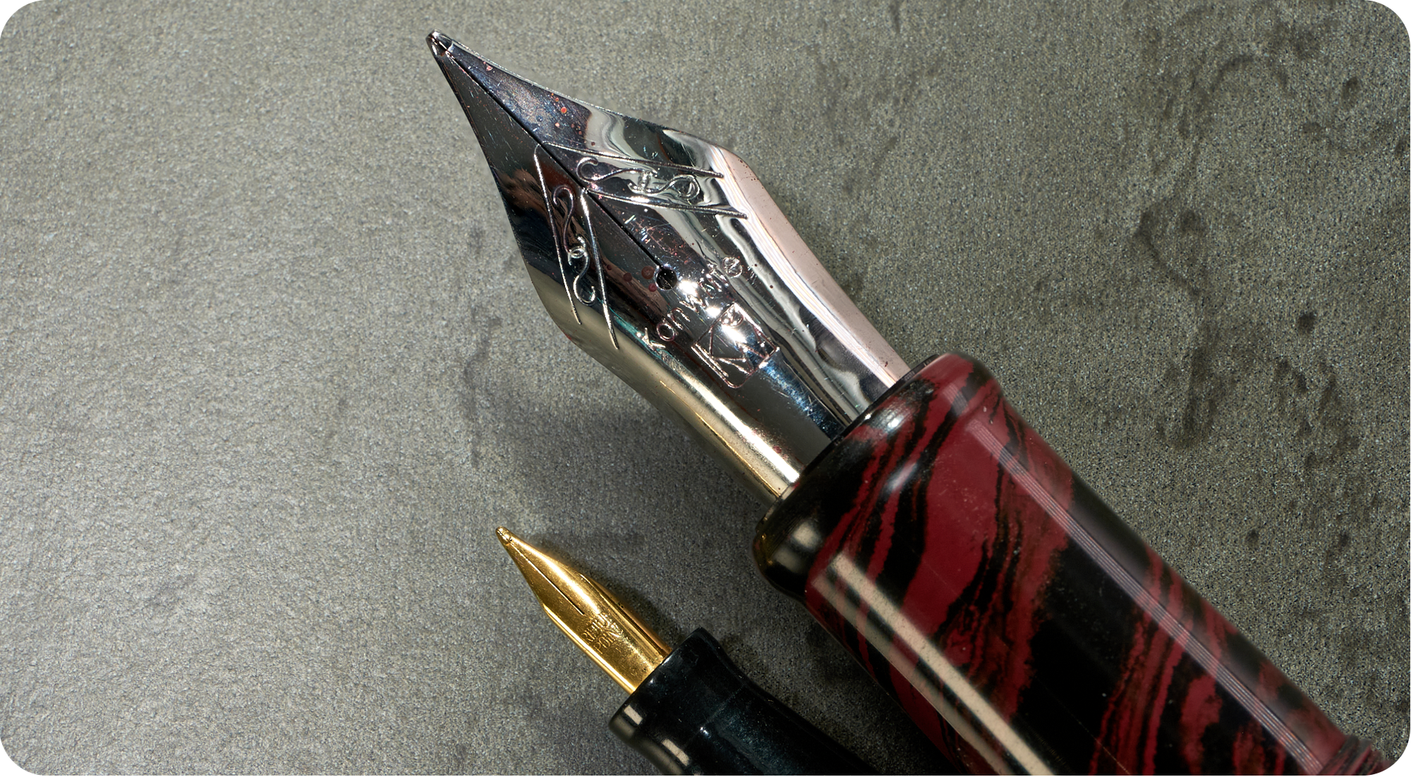 Photo of two fountain pen nibs, one huge & one tiny. 