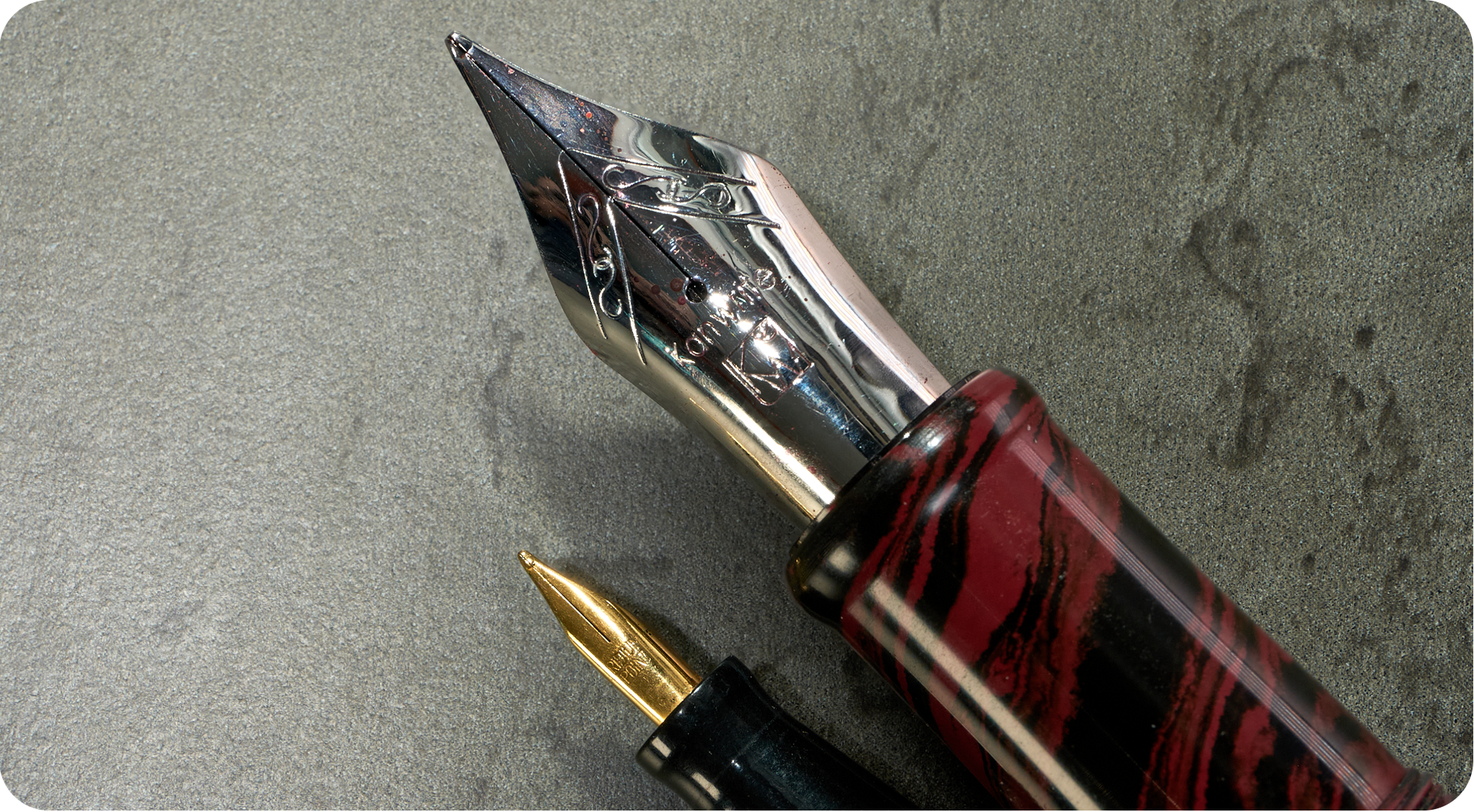 Photo of two fountain pen nibs, one huge & one tiny.